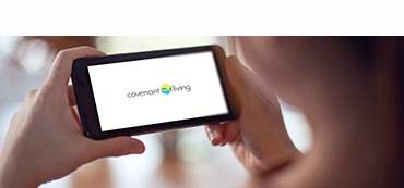 woman holding a phone with the covenant living logo
