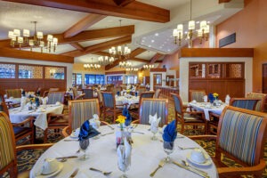 Indoor dining room filled with finely set tables with flower centerpieces