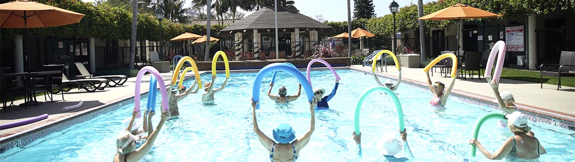 group of women holding up pool noodles in the water